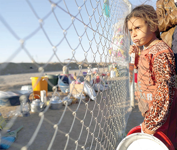 An Iraqi refugee girl waits with her parents to buy food from a local vendor behind the fence of the Khazir Refugee Camp near the Kurdish checkpoint of Aski Kalak, 40 km west of Erbil, the capital of the autonomous Kurdish region of northern Iraq, on Monday (AFP photo)